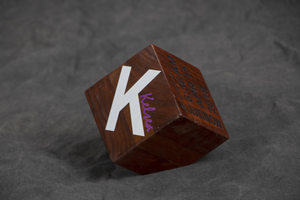 Cube shaped wooden award with large K on the front